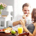 Picture of young couple eating breakfast in bed